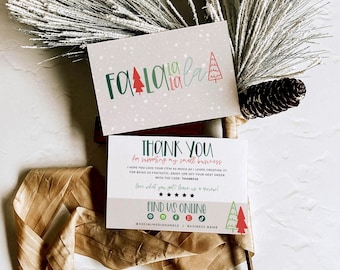 May include: Two rectangular cards with holiday themes. The top card features the text "fa la la la" in green and red with small tree icons. The bottom card says "THANK YOU for supporting my small business" with social media icons and a discount code.