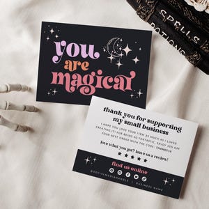 May include: Two rectangular cards. The top card is black with the pink and orange text 'you are magical' and white star and moon illustrations. The bottom card is white with black text, five black stars, and a black footer with pink text.