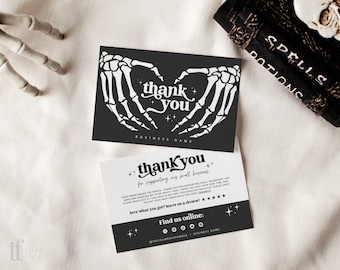 May include: Two rectangular business thank you cards. The top card is black with white skeleton hands forming a heart and the text thank you. The bottom card is white with black text thank you for supporting my small business and social media icons.