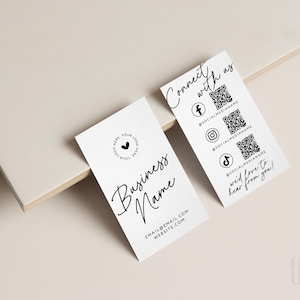 May include: Two white rectangular business cards with black text and graphics. One card features a logo placeholder, Business Name, and contact info. The other displays Connect with us, three QR codes, social media icons, and We'd love to hear from you!