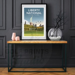 May include: A black framed print of a golf course with the Statue of Liberty in the background. The print has the text "Liberty National" and "13th. Par 5 - 563 Yards."