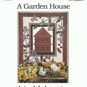 May include: A quilt pattern titled "A Garden House" by Thimbleberries. The pattern features a red and brown birdhouse with a vine of red berries and green leaves around it.