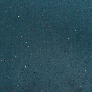 May include: A close-up of a dark teal fabric with a speckled pattern of red, yellow, and blue flecks.