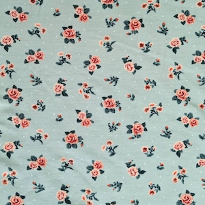 May include: A light blue fabric with a repeating pattern of small pink roses and white dots.