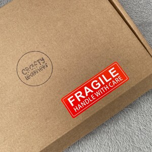 May include: A brown cardboard box with a red "Fragile Handle With Care" sticker and a black and white "Crafty Learners" stamp.
