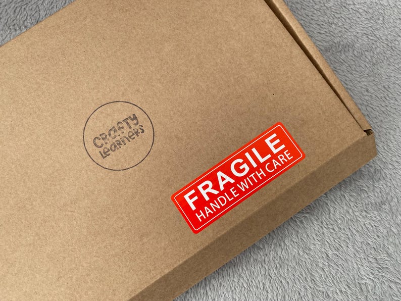 May include: A brown cardboard box with a red "Fragile Handle With Care" sticker and a black and white "Crafty Learners" stamp.