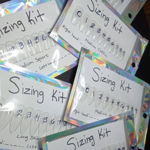 May include: Five clear plastic bags with white cards inside. Each card has a different nail shape and size labeled with numbers 0-9. The nail shapes are labeled as "Long Ball", "Medium Coffin", "Medium Square", "Long Stilet", and "Long Square".