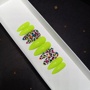 May include: A set of ten almond-shaped press-on nails featuring a glossy finish. Some nails are solid neon lime green, while others are clear with a vibrant multi-colored leopard print pattern in shades of neon pink, orange, blue, and black.