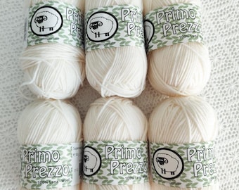 May include: Six skeins of off-white Primo Prezzo 100% Lana-Wool yarn are arranged in two rows. Each skein has a label with a sheep logo and the brand name. The yarn is soft and fluffy, ideal for knitting or crocheting projects.