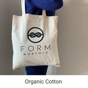 May include: A white tote bag with black handles and a black logo that says "FORM NORFOLK" with a stylized knot design. The bag is made of organic cotton.