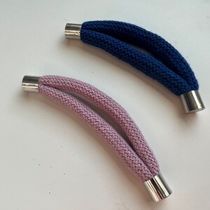 May include: Two knitted cords with metal ends. One cord is pink and the other is blue.