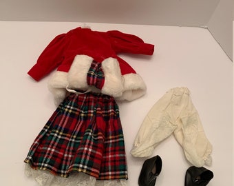Könnte beinhalten: Ein rotes Samt-Puppenkleid mit weißem Pelzbesatz, ein karierter Rock mit Spitzenbesatz, eine weiße Hose und schwarze Schuhe.
