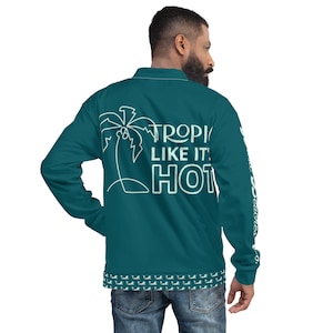May include: A teal blue bomber jacket with a palm tree and the text "TROPIC LIKE IT HOT" on the back. The jacket has a teal blue and white pattern on the bottom hem.