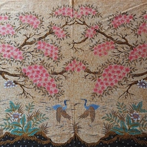 May include: A beige textile with a repeating pattern of pink flowering trees and stylized birds. The trees have brown branches and are filled with clusters of pink flowers. Two blue and brown birds are depicted in the center, with green and blue foliage at the bottom.