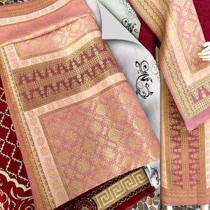 Pu&ograve; includere: Tessuto rosa e oro a fantasia con disegni intricati. Il tessuto presenta un motivo geometrico ripetuto e un bordo con un motivo floreale dettagliato. La tavolozza dei colori comprende sfumature di rosa, oro e bordeaux. Il tessuto &egrave; probabilmente utilizzato per scopi decorativi.