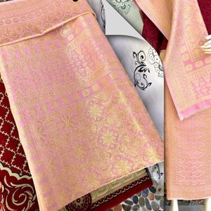 Pu&ograve; includere: Tessuto rosa e oro con intricati motivi floreali e geometrici. Il tessuto &egrave; piegato, rivelando il design dettagliato. Il tessuto &egrave; probabilmente un tessuto decorativo o un capo d'abbigliamento.