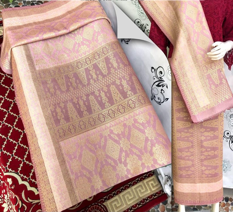 Pu&ograve; includere: Tessuto rosa e oro con motivi intricati. Il tessuto &egrave; drappeggiato per mostrare la sua consistenza e i dettagli. La tavolozza dei colori include sfumature di rosa e oro, creando un aspetto lussuoso. Il tessuto sembra essere un tessuto, forse per abbigliamento o arredamento.