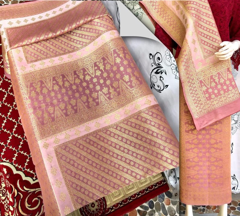 Pu&ograve; includere: Una collezione di tessuti rosa e oro con motivi intricati. I tessuti presentano disegni floreali e geometrici, con un mix di sezioni a tinta unita e fantasia. I tessuti sono probabilmente utilizzati per abbigliamento o arredamento.