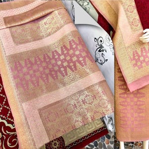 Pu&ograve; includere: Tessuto rosa e oro a motivi intricati. Il tessuto &egrave; piegato e drappeggiato, mettendo in risalto i motivi e le trame dettagliate. La tavolozza dei colori comprende sfumature di rosa, oro e marrone, creando un aspetto lussuoso.
