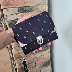 Una cartera con un gran compartimento circunferencial para monedas con motivo de ancla.