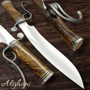 May include: A handcrafted knife with a polished steel blade and a wooden handle. The handle features a unique grain pattern and is accented with silver-colored metal. The word "Alghani" is written in cursive script near the bottom.