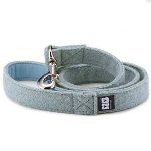 May include: A light blue dog leash made of tweed with a silver clip and a black label that says "MG Heritage".