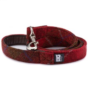 May include: Red and brown plaid dog leash with a silver clip and a black label that says "Heritage" with a logo.