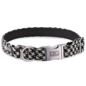 May include: Black and white houndstooth patterned dog collar with a silver buckle and D-ring. The collar is made by the brand "Ollie & George".