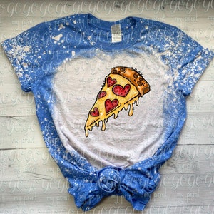 May include: A blue short-sleeve t-shirt with a bleached white center section. The graphic features a slice of pizza with melting cheese and red heart-shaped pepperoni slices. The shirt has a crew neckline and a knotted hem at the bottom.