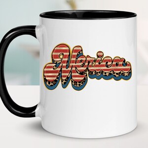 May include: White ceramic mug with a black rim and handle. The mug features a graphic of the word "Merica" in a retro font with red, white, and blue stripes and a leopard print pattern.