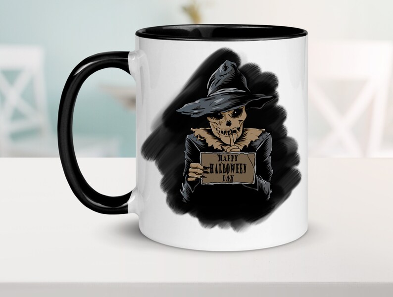 Peut inclure: Mug en c&eacute;ramique blanche avec une anse et un bord noirs. Le mug pr&eacute;sente une illustration en noir et blanc d'un squelette portant un chapeau de sorci&egrave;re et tenant une pancarte qui dit "Happy Halloween Day".