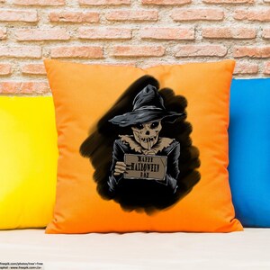 Peut inclure: Un coussin orange avec une illustration en noir et blanc d'un &eacute;pouvantail tenant une pancarte qui dit "Joyeux Halloween".