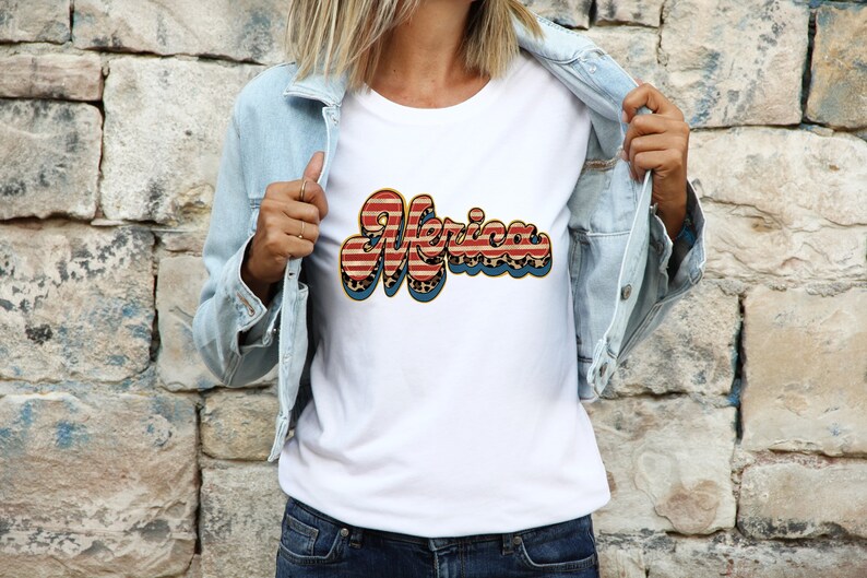 May include: White t-shirt with a red, white, and blue "Merica" graphic. The graphic is in a retro font and features a leopard print pattern.
