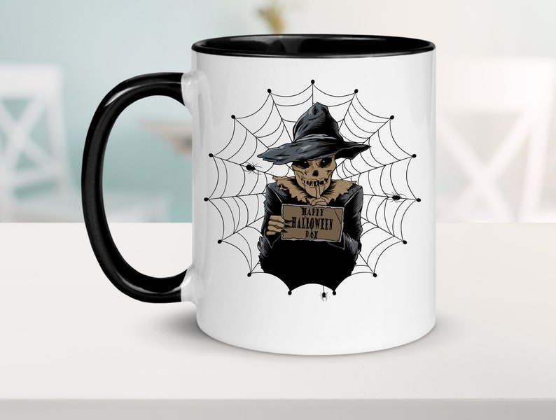 K&ouml;nnte beinhalten: Eine wei&szlig;e Keramiktasse mit schwarzem Henkel und Rand. Die Tasse zeigt eine Schwarzwei&szlig;illustration eines Skeletts, das einen Hexenhut tr&auml;gt und ein Schild mit der Aufschrift "Happy Halloween Day" vor einem Spinnennetz-Hintergrund h&auml;lt.