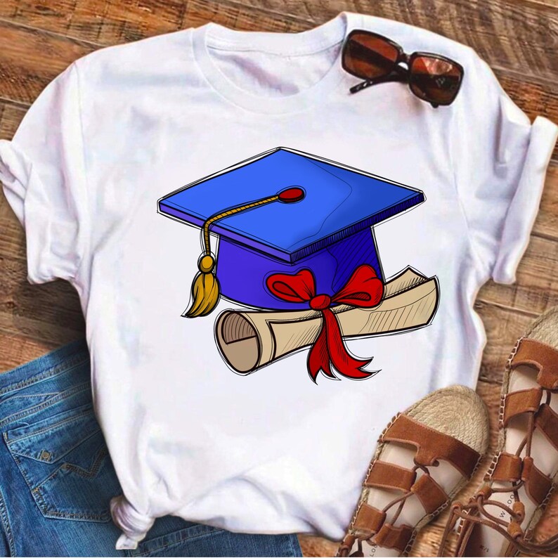 May include: White t-shirt featuring a blue graduation cap and a rolled up diploma tied with a red ribbon.