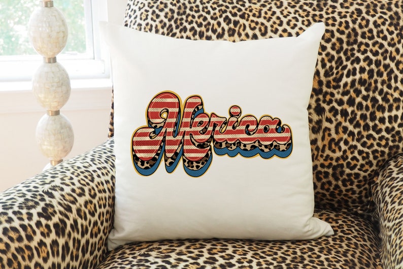 May include: White throw pillow with a red, white, and blue "Merica" graphic in a retro font. The graphic has a leopard print pattern and blue and yellow outlines.