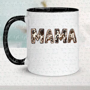 Puede incluir: Taza de caf&eacute; de cer&aacute;mica blanca con asa negra y borde negro. La taza tiene un dise&ntilde;o de estampado de vaca marr&oacute;n y blanco con la palabra "MAMA" en letras marrones.
