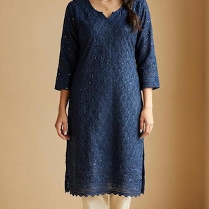 May include: A navy blue tunic with a V-neck and three-quarter sleeves, featuring intricate embroidery. The tunic is paired with cream-colored pants. The outfit is suitable for casual or semi-formal occasions.