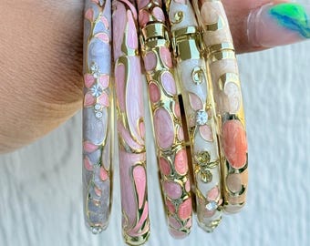May include: Set of six decorative bangles in shades of pink, white, and gold. The bangles feature floral and abstract designs with gold accents. The text "Set 3" is in the upper left corner.