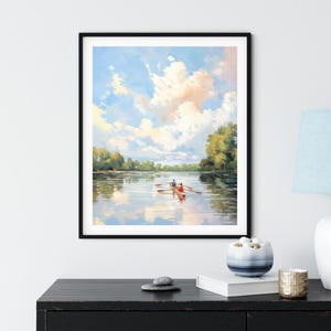 May include: A framed painting depicts a serene river scene with a rowboat carrying two people. The sky is filled with fluffy clouds, reflecting in the water. The artwork is framed in a black frame and displayed on a black surface.