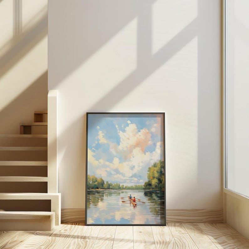May include: A framed landscape painting depicts a serene river scene with a rowboat. The sky is filled with fluffy clouds, reflecting in the water. The artwork is in a black frame, leaning against a white wall, next to a staircase.