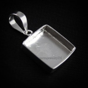 Op de afbeelding: Zilveren hanger met een vierkante bezel-setting. De hanger heeft een lus om een ketting aan te bevestigen. De bezel is leeg en klaar om te worden gevuld met een steen of ander materiaal.