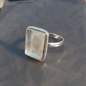 May include: Silver ring with a square bezel setting. The bezel is empty and ready to be filled with a stone or other material.
