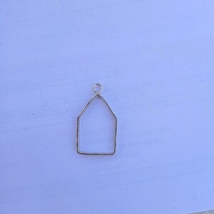May include: A silver metal house-shaped pendant with a loop at the top for hanging.