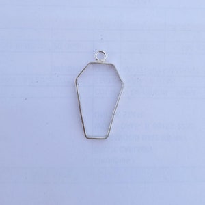 Peut inclure: Pendentif en métal argenté en forme de cercueil. Le pendentif a une boucle en haut pour l'attacher à une chaîne ou un cordon.