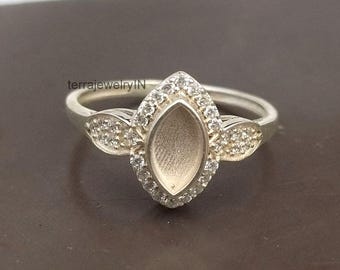 Op de afbeelding: Een zilveren ring met een marquise-vormige zetting, omringd door kleine, heldere stenen. De ring heeft een delicaat ontwerp met extra stenen accenten aan de zijkanten. De merknaam "terrajewelryIN" is zichtbaar.