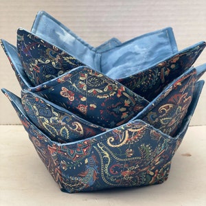 Peut inclure: Un ensemble de trois protège-bols en tissu bleu et blanc à motif paisley. Les protège-bols sont pliés et empilés les uns sur les autres.
