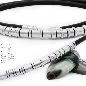 May include: A black leather necklace with silver beads and a silver clasp. The necklace is shown with two green and white agate stones.
