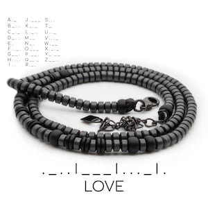 May include: A black beaded necklace with a silver clasp and chain. The necklace is coiled and the text "LOVE" is written below the necklace.