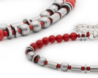 May include: Two bracelets with red and silver beads. The larger bracelet has a chain clasp. The smaller bracelet has a silver toggle clasp.